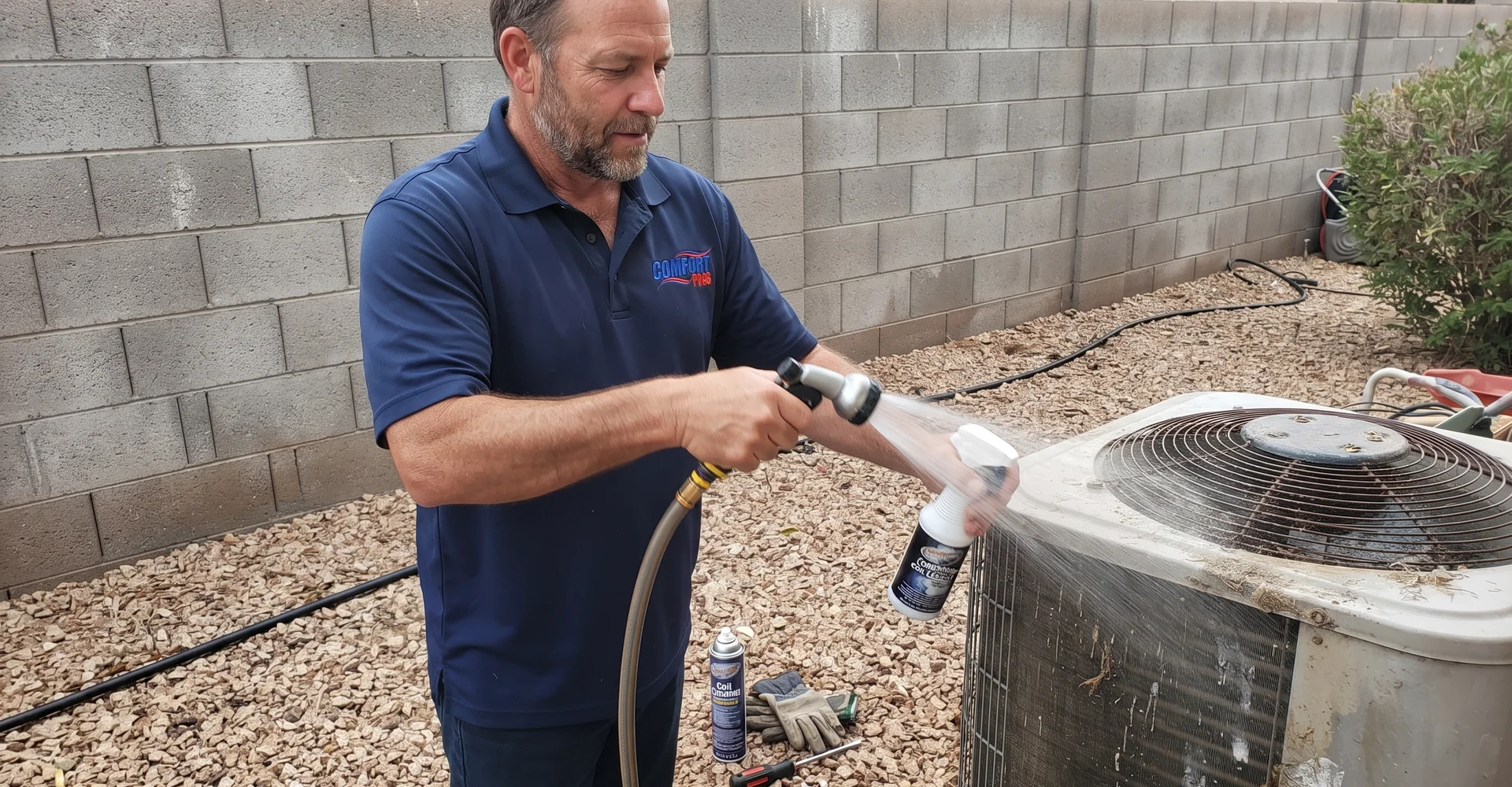 Technician cleaning a residential condenser coil during a seasonal tune-up