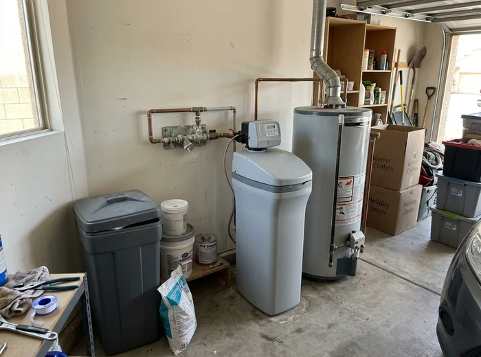 Water softener installed beside a water heater in a garage
